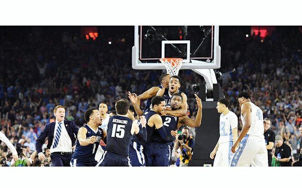 Ecstatic teammates mob Villanova’s Kris Jenkins (2) after he shot the winning three-point basket to upset the University of North Carolina 77-74 and secure his school’s first NCAA men’s Division I hoops championship since 1985. Just four-tenths of a second were left on the clock when the game-ending shot left his hands. His shot came just 4.3 seconds after UNC’s Marcus Paige hit an off-balance 3-pointer to tie the game, seemingly sending it to overtime. 