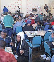 Community members enjoy food and conversation last Friday at Centenary United Methodist Church’s lunch program at the former Aurora nightclub at 4th and Grace streets in Downtown. Below, Dr. Matt Bates, right, pastor of Centenary United Methodist Church, and Al Richardson, the church’s facilities manager, help spearhead the longtime weekly feeding program.