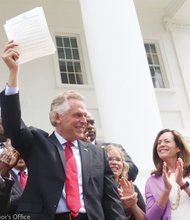 Gov. Terry McAuliffe triumphantly holds up the historic order he signed last Friday outside the state Capitol. 