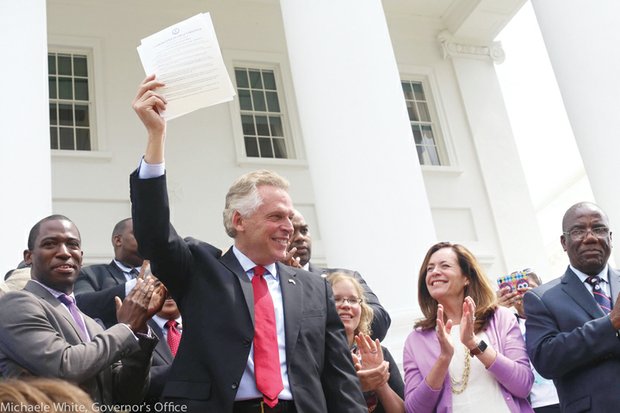 Gov. Terry McAuliffe triumphantly holds up the historic order he signed last Friday outside the state Capitol. 