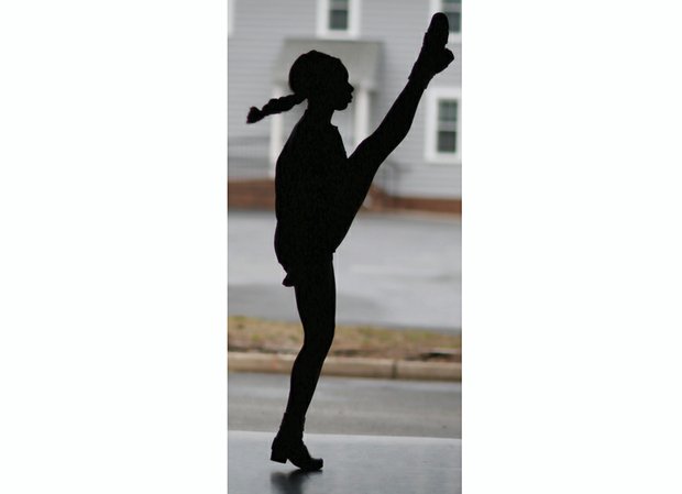 Morgan Bullock, seen in silhouette, practices one of the intricate and athletic Irish dance moves. Location: Baffa Academy of Irish Dance in Chesterfield County.
