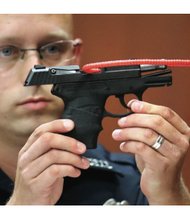 Sanford, Fla., police officer Timothy Smith holds up the 9mm handgun used to kill Trayvon Martin during the 2013 murder trial of George Zimmerman. Mr. Zimmerman was acquitted of second-degree murder in the slaying of the unarmed 17-year-old.