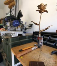 Roses of remembrance are crafted in Anthony Vella’s garage at Fort Lee. A steel rose is mounted on a wood block and adorned with dog tags.