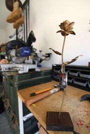 Roses of remembrance are crafted in Anthony Vella’s garage at Fort Lee. A steel rose is mounted on a wood block and adorned with dog tags.