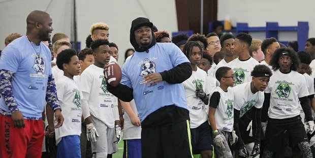 Marshawn Lynch, who retired earlier this year from the Seahawks, prepares to throw a pass to campers.
Below, Maurice Canady, a standout at Varina High School and the University of Virginia who was drafted just weeks ago in the sixth round by the Baltimore Ravens, takes a moment to encourage camp participant Debin Raines.