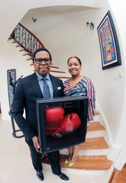 Dr. Monroe Harris and his wife, Dr. Jill Bussey, show boxing gloves autographed by the champ, who grew up in the same neighborhood with them in Louisville, Ky.