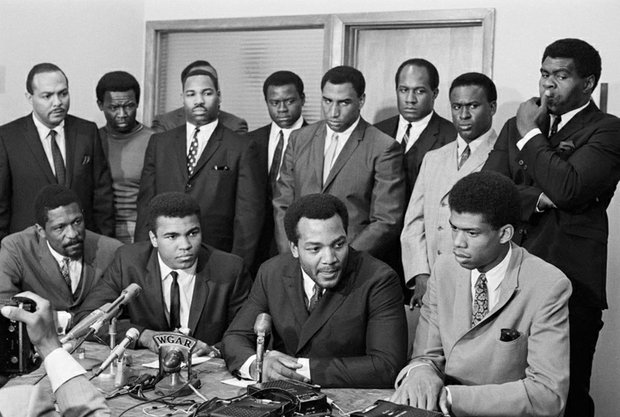 
Sports stars take part in the 1967 “Ali Summit” in Cleveland to show support for the boxing champ’s refusal to be drafted. Mr. Ali, seated second from left, was joined by, seated from left, Bill Russell, Boston Celtics; Jim Brown, Cleveland Browns, and then college star Lew Alcindor Jr., later L.A. Lakers great Kareem Abdul-Jabbar. Standing from left: Ohio Congressman Carl Stokes; Walter Beach, Cleveland Browns; Bobby Mitchell, Washington NFL team; Sid Williams, Cleveland Browns; Curtis McClinton, Kansas City Chiefs; Willie Davis, Green Bay Packers; Jim Shorter, former Cleveland Browns player and John Wooten, Cleveland Browns.