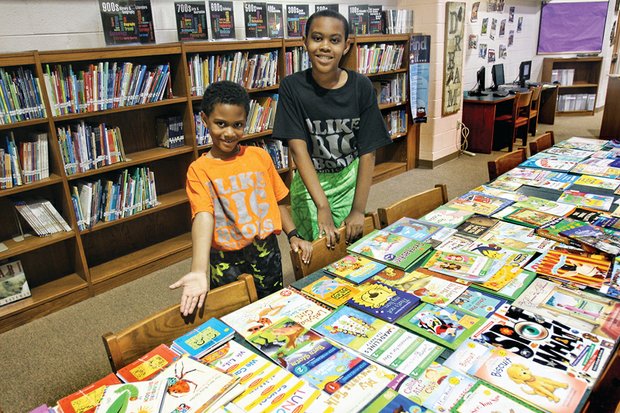 Brothers Jace, 7, left, and Jazz Miles, 10, show off some of the 1,400 books they collected to give to their fellow students at Richmond’s Linwood Holton Elementary School. The boys’ efforts mean that Holton’s 600 students will have at least two books of their own to read during summer break.
