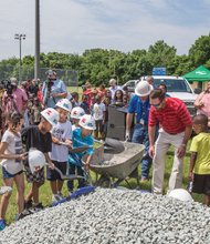 Todd “Parney” Parnell, vice president and chief operating officer of the Richmond Flying Squirrels baseball team, right, guides a cadre of youngsters at last Thursday’s ceremony announcing the baseball field makeover at Charlie D. Sydnor Playground in South Richmond.