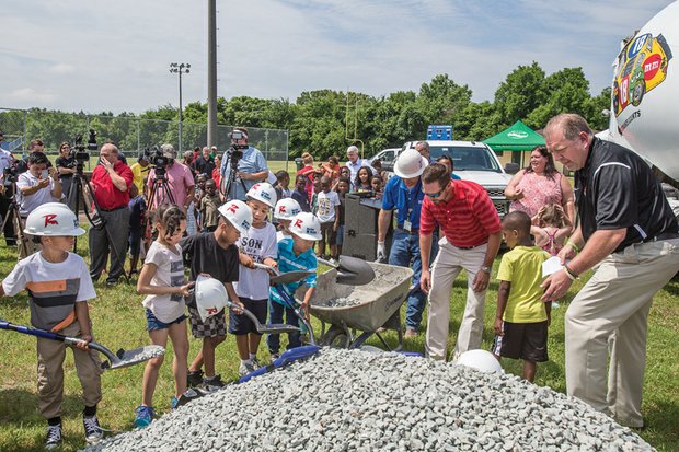 Todd “Parney” Parnell, vice president and chief operating officer of the Richmond Flying Squirrels baseball team, right, guides a cadre of youngsters at last Thursday’s ceremony announcing the baseball field makeover at Charlie D. Sydnor Playground in South Richmond.