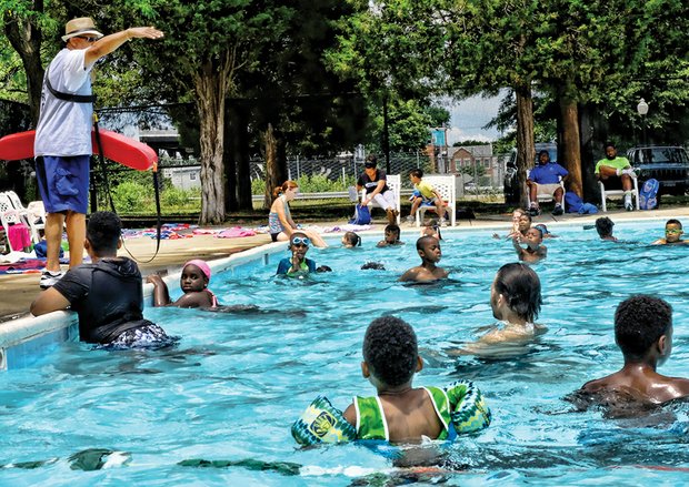 Pool supervisor Clarence Bey directs swimmers Wednesday as children and adults beat the heat in the city’s Randolph Pool in the West End. The city’s outdoor pools opened June 18, just in time for the summer heat, and will be open seven days a week through Labor Day. 