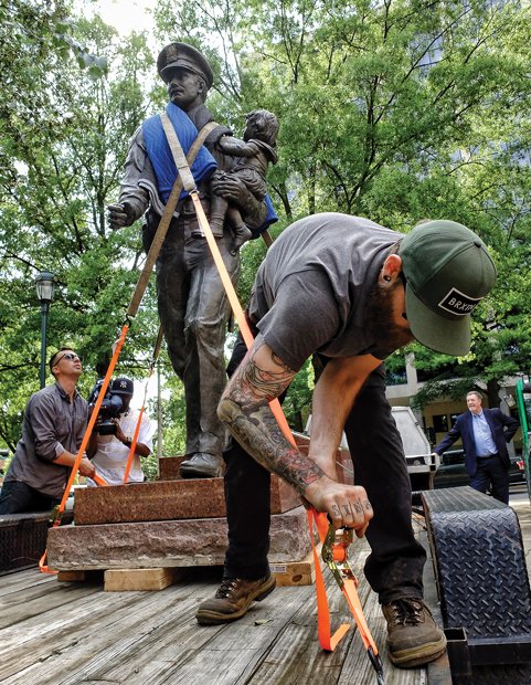 Cityscape // The memorial statue honoring 28 Richmond police officers killed in the line of duty since 1869 is moved to a new home, as shown in this series of photographs. Left, Travis Moss tightens a strap to secure the 8-foot bronze statue and its granite base for the trip last Friday from Festival Park near the Richmond Coliseum in Downtown to Byrd Park.