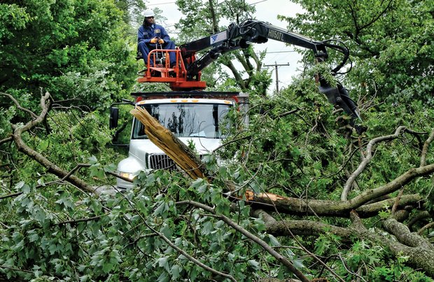 Cleanup is still underway after the June 16 storm. Here a city worker uses heavy machinery to pick up a mass of fallen limbs on Claremont Avenue. More than 900 city trees were toppled during the event, and some were weakened enough to fall days later.  