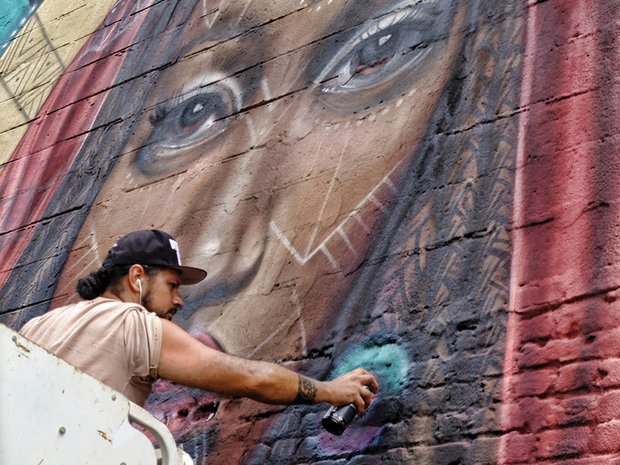 Victor “Marka27” Quiñonez adds finishing touches to his new “Givers of the Divine” mural. Location: 6 W. Cary St. in Downtown. From Brooklyn, N.Y., Mr. Quiñonez is among a dozen visiting artists who painted more than 14 murals on buildings during this summer’s Richmond Mural Project, which ended last week.