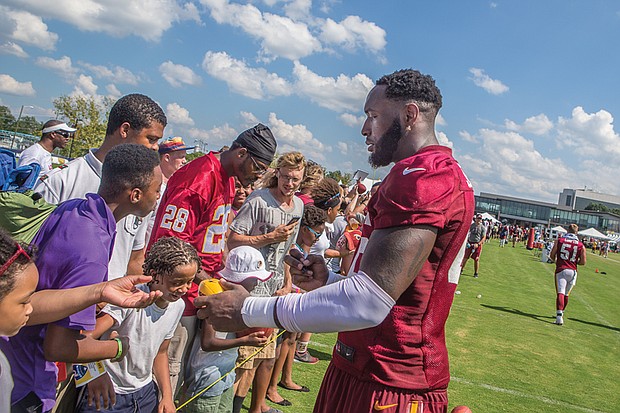 Big thanks for big fans //Willie Jefferson, right, hands an autographed mini football to another fan.
The event featured musical performances and dance competitions before the team’s practice. After practice, team members mingled with the crowd.