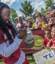 Big thanks  for big fans //  The Washington NFL team wrapped up its Richmond training camp Sunday, but not before hosting its traditional Fan Appreciation Day last Saturday.
With the line of fans wrapped around West Leigh Street, the Bon Secours training center was mobbed with autograph seekers of all ages.
Cornerback Greg Toler, left, a graduate of the former St. Paul’s College in Lawrenceville, signs a hat for Aniya Neeson,