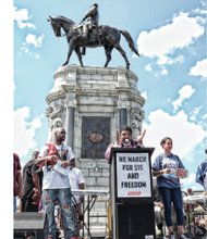 Dr. William Barber II, left, president of the North Carolina NAACP, energizes the crowd of thousands who withstood Saturday’s scorching heat to march from Monroe Park to the Monument Avenue statue of Confederate Gen. Robert E. Lee to call for an end to slave wages. 