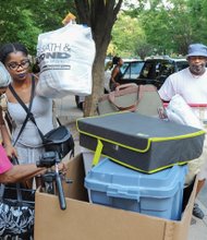 Freshman Selina Sykes of Baltimore, center, receives a helping hand from her grandmother, Albertha Sykes, and her dad, Lee Sykes, as she moves into Virginia Commonwealth University’s Johnson Hall last Saturday. Parents, relatives and friends formed the line of movers at the West Franklin Street residence hall. 