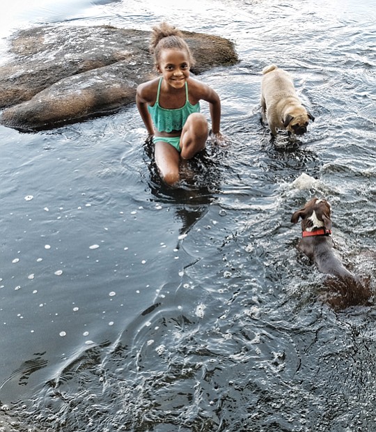 Last splash before school // Alanna Runger enjoys an end-of-summer swim Wednesday in the Pony Pasture Rapids on South Side with her playful pug, Ye Ye, and
Joy, the friendly Boston terrier. Her mother and sister, not pictured, were also along for the fun. The Labor Day holiday weekend will see cooler temperatures in the 70s on Saturday and Sunday with rain possible. Showers are expected to move out by Monday, with highs in the mid-80s. Area schools will open Tuesday to a forecast of sunny skies, with temperatures in the high 80s.