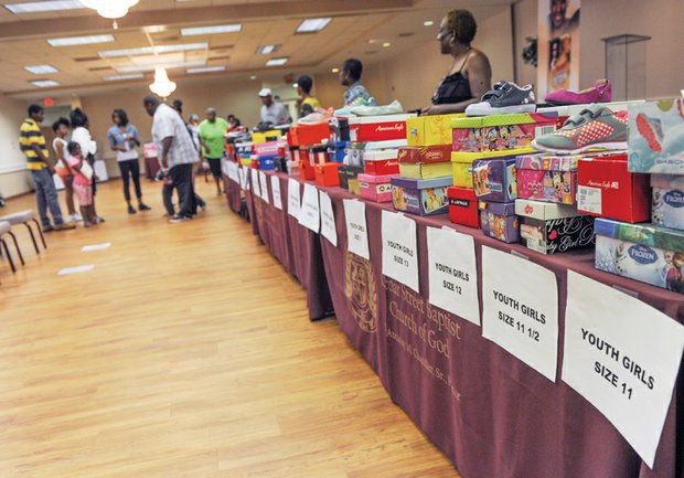 Kicks for kids // Below, volunteers wait to assist the students in a mock shoe store created in the fellowship hall. Excited youngsters could be fitted for the appropriate shoe size before selecting from a wide assortment.