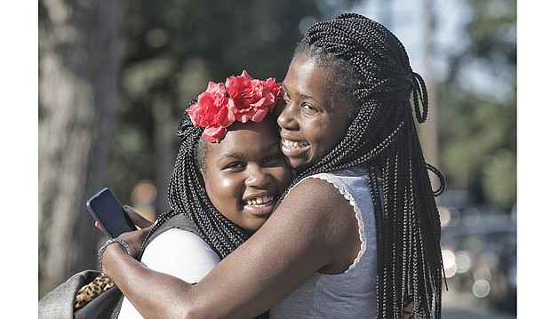 Sixth-grader Ayanna Street, left, and her mother, Yakysha Langhorne, embrace during a first-day-of-school pep talk
while waiting at the bus stop Tuesday at Westover Hills Elementary School. The South Side elementary school is
Ayanna’s hub to get to Binford Middle School in the West End under the new transportation plan.