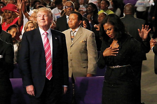 Republican presidential nominee Donald Trump, left, is accompanied by Steve Parson of Richmond and Omarosa Manigault, former contestant on “The Apprentice” and director of African-American outreach for the Trump campaign, during his visit last Saturday to an African-American church in Detroit. 