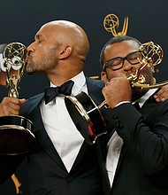 Funnymen Keegan-Michael Key, left, and Jordan Peele kiss their Emmy Awards after the show. They won the Emmy for outstanding variety sketch series for their comedy show, “Key & Peele.”