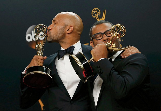 Funnymen Keegan-Michael Key, left, and Jordan Peele kiss their Emmy Awards after the show. They won the Emmy for outstanding variety sketch series for their comedy show, “Key & Peele.”