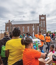 Sixth Mount Zion Pastor Tyrone Nelson, center, adds household items to an array of goods, clothing and food
that were given away last Sunday by the congregation in Jackson Ward.