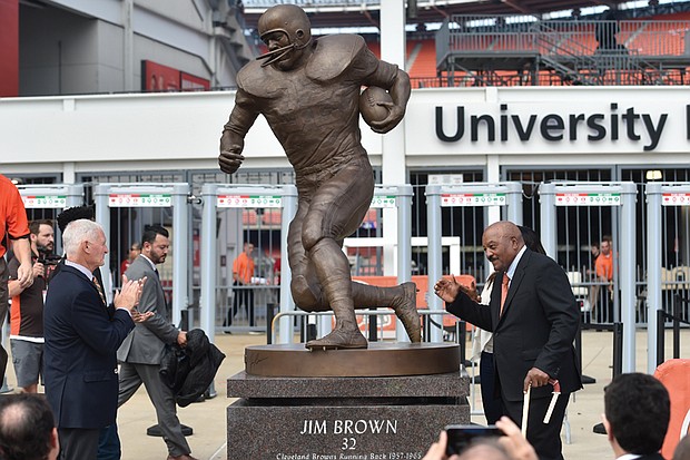 Football icon Jim Brown, right, strikes a pose with the statue of himself that now stands outside the stadium of his former team, the Cleveland Browns. The statue of the pro football hall of famer who ranks among the all-time great running backs was unveiled Sept. 18.