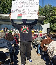  
A protester walks through the crowd during the Lumpkin’s Jail ceremony to raise awareness of the mass incarceration of African-Americans in the United States. The event also marked the 216th anniversary of the execution of slave revolt leader Gabriel Prosser on the grounds.  