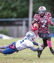 Thomas Jefferson High School’s Kahli Andrews skirts past John Marshall High defensive player Andre Haden during last Friday’s big rivalry game at TJ’s home field. The Vikings beat the Justices 21-16. 