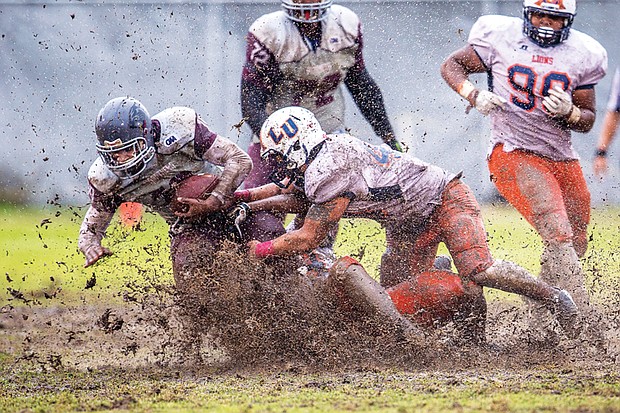 Virginia Union University junior Kevin Green carries the ball through the mud bowl during the Panthers’ homecoming game last Saturday at Hovey Field. The Panthers beat the Lincoln University Lions 39-6.