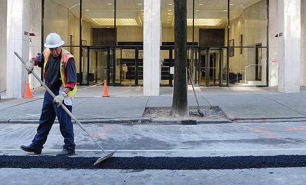 A worker smooths fresh asphalt filling a trench in the street created for installation of a utility line. Location: 800 block of East Main Street in Downtown. Dozens of repair and street projects are underway across the city, creating detours and other temporary disruptions for motorists. 