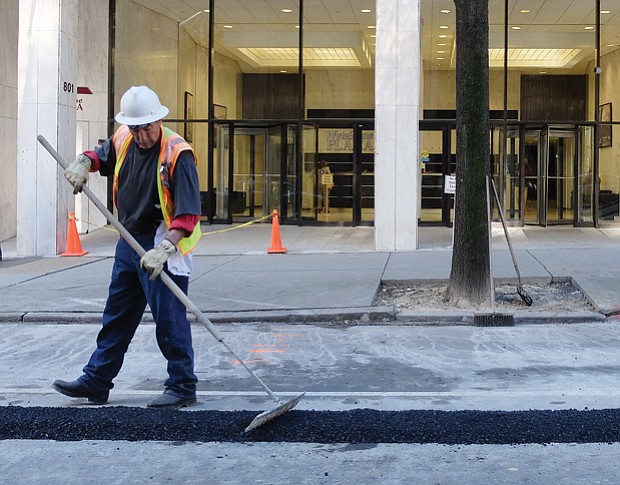 A worker smooths fresh asphalt filling a trench in the street created for installation of a utility line. Location: 800 block of East Main Street in Downtown. Dozens of repair and street projects are underway across the city, creating detours and other temporary disruptions for motorists. 