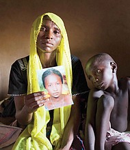 Rachel Daniel, 35, holds a photo of her 17-year-old daughter, Rose, who was abducted with more than 200 classmates on May 21, 2014, by Boko Haram militants from her school in Chibok, Nigeria. Rose’s brother, Bukar, 7, sits with his mother.