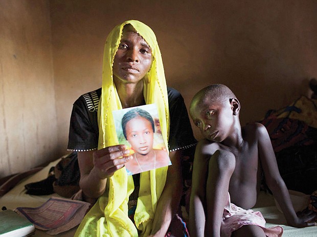 Rachel Daniel, 35, holds a photo of her 17-year-old daughter, Rose, who was abducted with more than 200 classmates on May 21, 2014, by Boko Haram militants from her school in Chibok, Nigeria. Rose’s brother, Bukar, 7, sits with his mother.