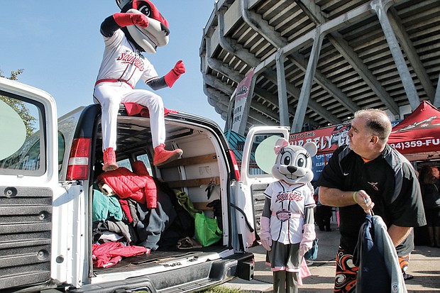 Warming hearts one coat at a time // Todd “Parney” Parnell, vice president and chief operating officer of the Richmond Flying Squirrels, works with team mascots Nutzy, left, and Nutasha to load coats in a van last Saturday during the 8th Annual Coats for Kids and Ballpark Warming Party at The Diamond. 
The Flying Squirrels were working with Coats for Kids sponsor, Puritan Cleaners, which collects about 15,000 coats for youngsters each November. The donated coats are washed, repaired and delivered to the Salvation Army for distribution to needy families in Central Virginia.
The collection event at The Diamond was part of the free Ballpark Warming Party, where fans of all ages enjoyed live music, chili tasting, crafts, games and raffle prizes, including baseball memorabilia.