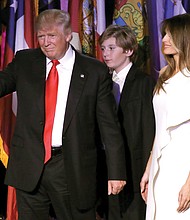 President-elect Donald Trump gestures to the crowd as he takes the stage to declare victory about 3 a.m. Wednesday at a rally in New York. His wife, Melania, and son, Baron, accompany him.