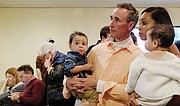 Mayoral candidate Joe Morrissey and his wife, Myrna, watch election results Tuesday night at his North Side campaign office. They hold their children, Chase, left, and Bella.