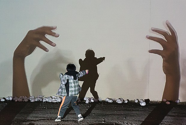 In the light //
A youngster interacts with Miatta Kawinzi’s art installation “Gatherin’ Place” during InLight Richmond 2016, an annual one-night, free outdoor exhibition of light-based art and performances organized by 1708 Gallery. This year’s event was held last Friday in Scott’s Addition, where people wandered among the creative array of lighted exhibits on walls, pathways, sidewalks and green spaces. Jellyfish-shaped lanterns were part of the event’s kickoff Community Lantern Parade.
