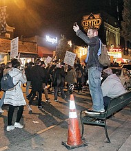 Protesters chant and carry signs as they march east on Cary Street during an anti-Trump demonstration that lasted several hours.  Right, Virginia Commonwealth University student Brianna Scott weeps during the anti-Trump “RVA Grabs Back Rally” last weekend.