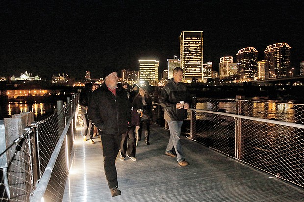 The first pedestrians stream across the newly opened T. Tyler Potterfield Memorial Bridge over the James River. Mayor Dwight C. Jones led the ribbon-cutting for the lighted bridge during the Grand Illumination on Friday. Richmond poured $11.3 million in state and city funds into the span open only to pedestrians and bikes. The new river crossing sits above a 1901 dam and links Brown’s Island on the North Side to an overlook on the South Side near the entry to the Manchester Bridge. Another $200,000 was spent on eight, 17-foot-tall metal rings that Denver artist Joshua Wiener created to adorn the South Side path to the 1,600-foot bridge. The bridge is named for a senior city planner who advocated for the bridge before his death in 2014.  Construction began in October 2015 on the only current city structure named for a city employee.  