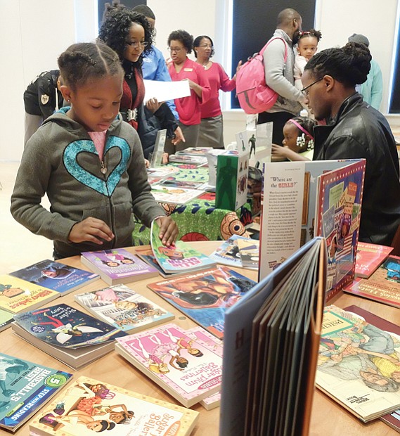 Open house at museum // Dozens of families enjoyed refreshments, arts and crafts, activities and exhibits at the annual Holiday Open House at the Black History Museum and Cultural Center of Virginia, featuring Soul Santa.
Above, Ma’Tazia Wormley, 7, inspects the selection of free books donated by Sistahs Book Club, while Ronnie Nelson Sidney, right, author of the highly acclaimed children’s book “Nelson Beats the Odds,” signs copies of his book. 
