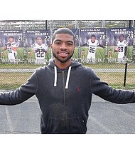 Senior Chris Thaxton, the Highland Springs High School wide receiver who scored the winning touchdown giving the Springers the state football title, stands Wednesday amid banners of the championship team members showcased outside the Henrico County school. Below, the football helmet worn by Thaxton is adorned with a purple ribbon, angel wings and the insignia “AngieStrong,” honoring his mother and team booster, Angela “Angie” Johnson.