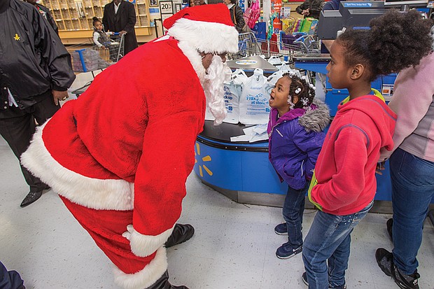 
Kevasia Taylor, 5, center, takes a break from shopping to rattle off her detailed Christmas list to Santa Claus, while 10-year-old Quanasia Hubbard waits to share her list during the Prince Hall Masons’ Operation Santa Claus last Saturday. Location: Walmart on Sheila Lane in South Side. 