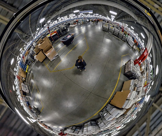 Employees work among a maze of conveyor belts and sorting machines in the huge building that is the size of 12 football fields and handles mail from Central and Eastern Virginia. Left, Free Press photographer Sandra Sellars seeks to give a sense of the building’s size by photographing a portion of the center reflected in a ceiling mirror. 