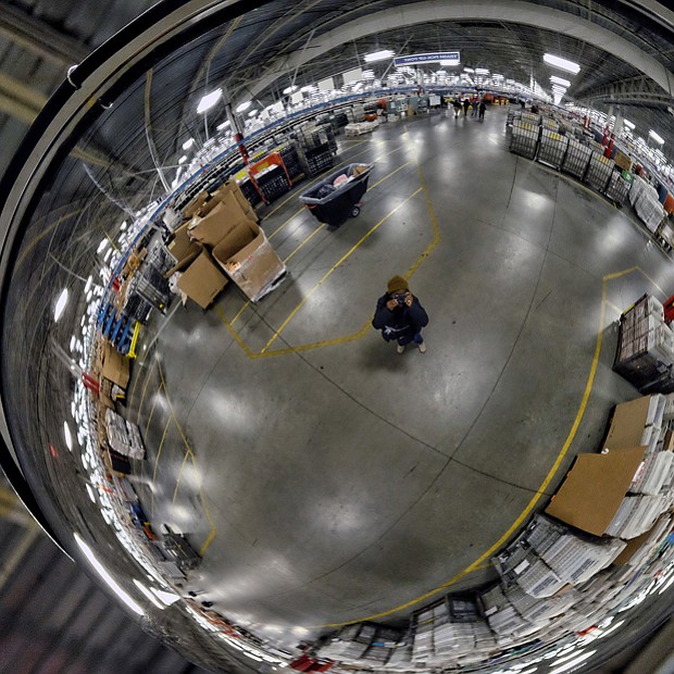 Employees work among a maze of conveyor belts and sorting machines in the huge building that is the size of 12 football fields and handles mail from Central and Eastern Virginia. Left, Free Press photographer Sandra Sellars seeks to give a sense of the building’s size by photographing a portion of the center reflected in a ceiling mirror. 