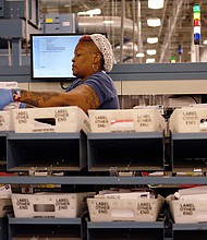 Taura James, above, sorts through the flood of letters and packages that have poured into the U.S. Postal Service’s Richmond Processing and Distribution Center in Sandston in Eastern Henrico County. Postal service officials showed off the plant Monday — the center’s busiest day that saw hundreds of employees handle  more than 2.4 million letters, cards and holiday packages. 