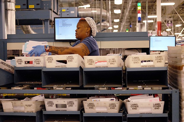 Taura James, above, sorts through the flood of letters and packages that have poured into the U.S. Postal Service’s Richmond Processing and Distribution Center in Sandston in Eastern Henrico County. Postal service officials showed off the plant Monday — the center’s busiest day that saw hundreds of employees handle  more than 2.4 million letters, cards and holiday packages. 